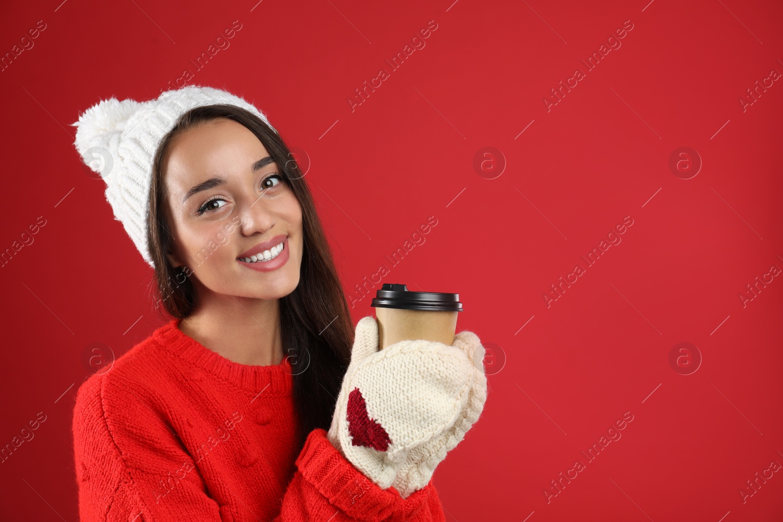 Photo of Happy beautiful woman with paper cup of mulled wine on red background. Space for text