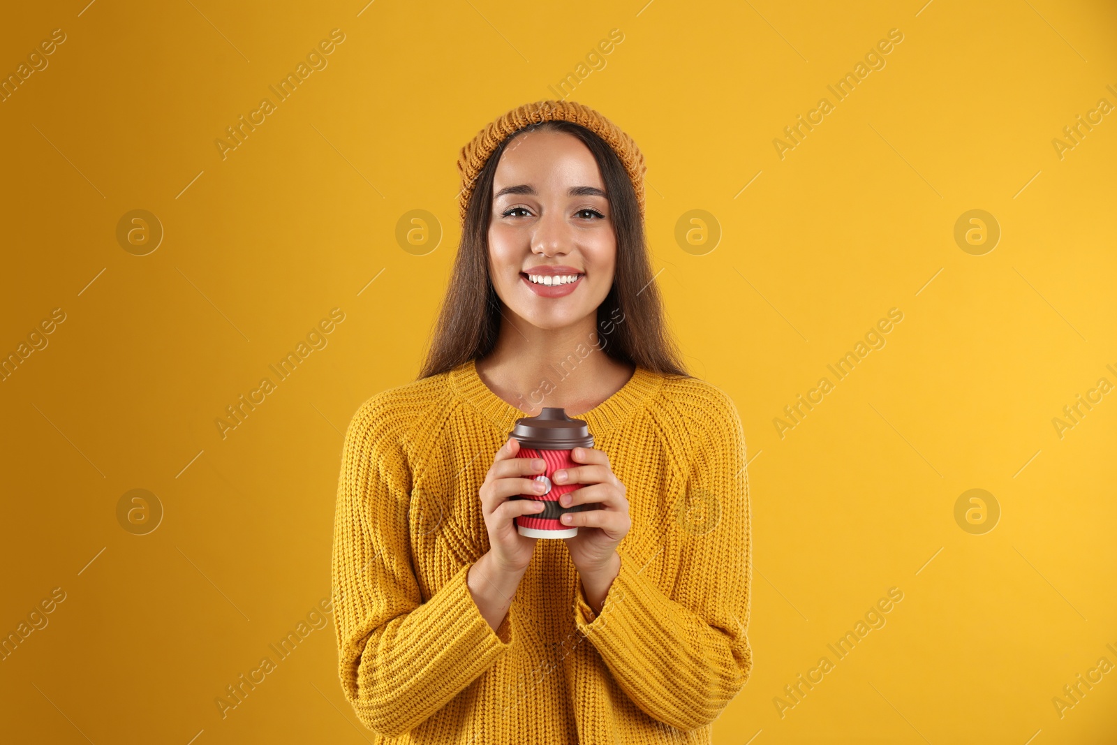 Photo of Happy beautiful woman with paper cup of mulled wine on yellow background