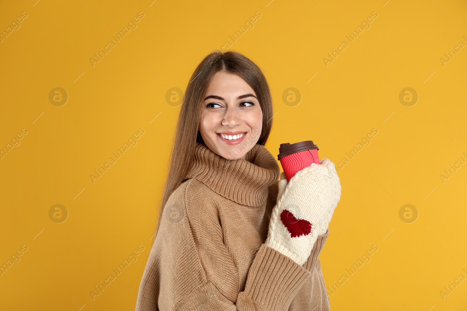 Photo of Happy beautiful woman with paper cup of mulled wine on yellow background