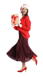 Woman in Santa hat, knitted mittens and red sweater holding Christmas gift on white background