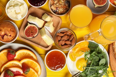 Photo of Different tasty food served for brunch on yellow wooden table, flat lay