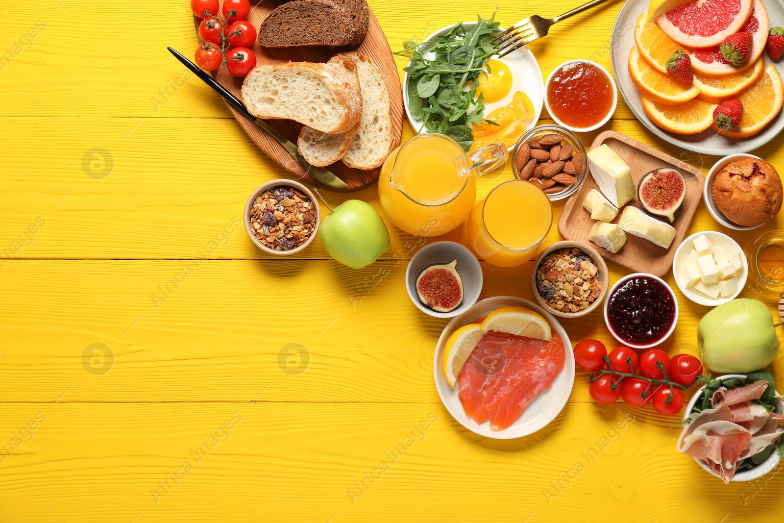 Photo of Different tasty food served for brunch on yellow wooden table, flat lay. Space for text