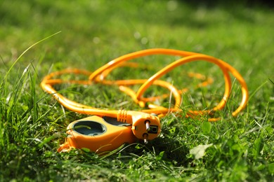 Photo of Orange extension cord on green grass outdoors, closeup