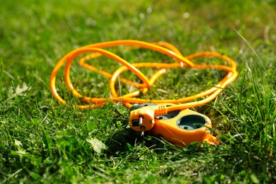 Orange extension cord on green grass outdoors, closeup