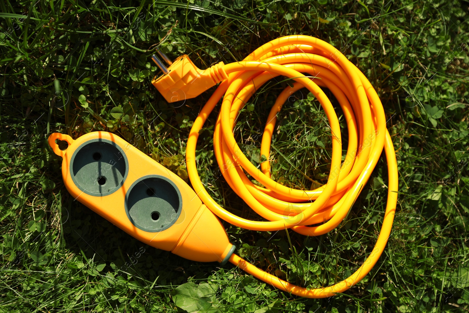 Photo of Orange extension cord on green grass outdoors, top view