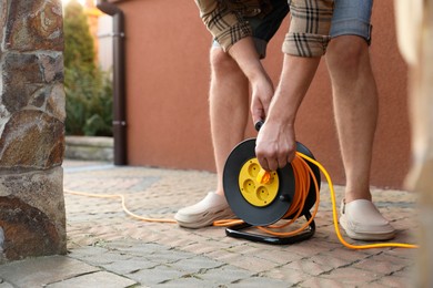 Photo of Man with extension cord reel outdoors, closeup