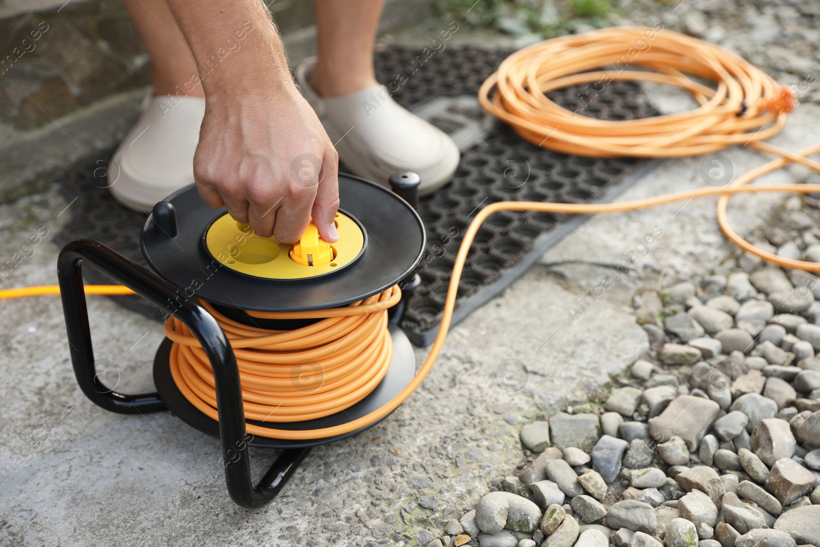 Photo of Man with extension cord reel outdoors, closeup