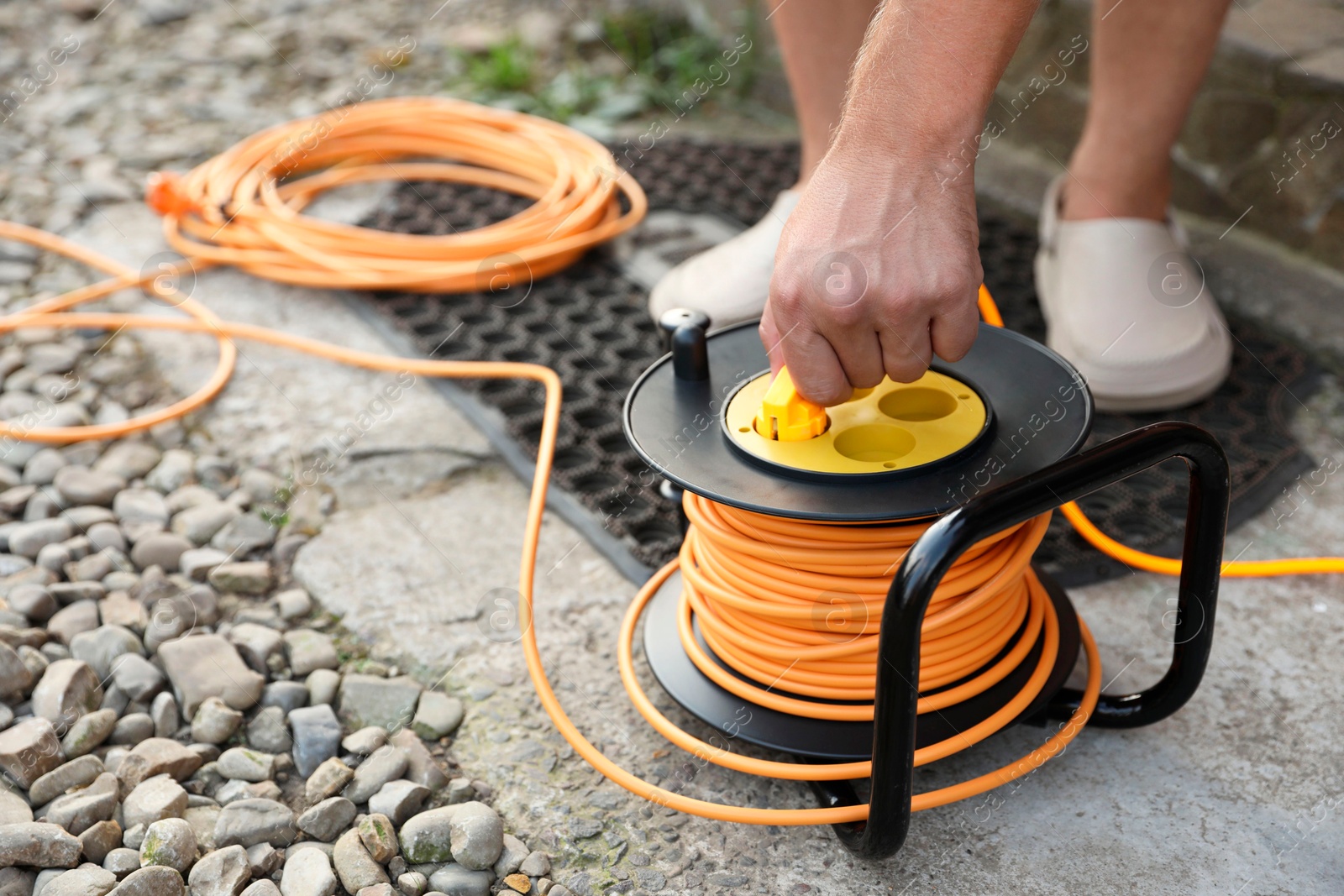 Photo of Man with extension cord reel outdoors, closeup