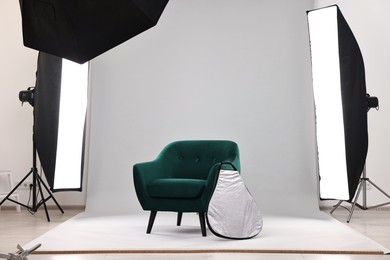 Photo of Professional lighting equipment setup and armchair in modern photo studio