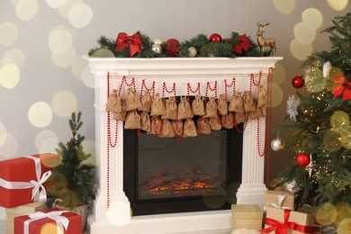 Photo of Advent calendar with gifts and decor hanging on fireplace Christmas near tree indoors