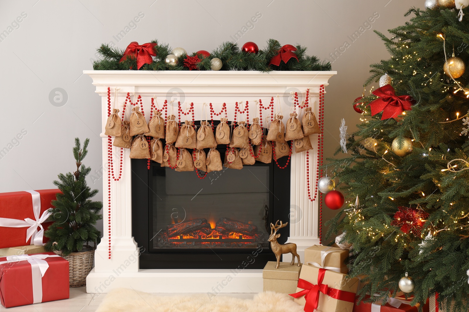 Photo of Advent calendar with gifts and decor hanging on fireplace Christmas near tree indoors