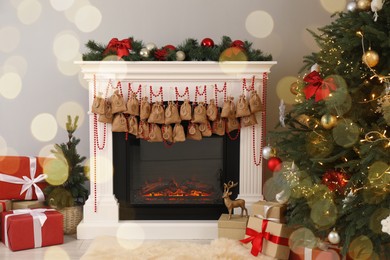 Photo of Advent calendar with gifts and decor hanging on fireplace Christmas near tree indoors