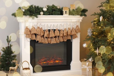 Photo of Advent calendar with gifts and decor hanging on fireplace Christmas near tree indoors