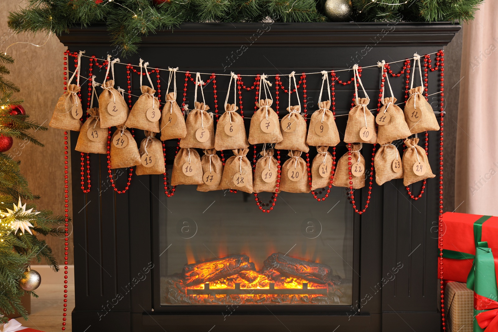 Photo of Advent calendar with gifts and decor hanging on fireplace Christmas near tree indoors