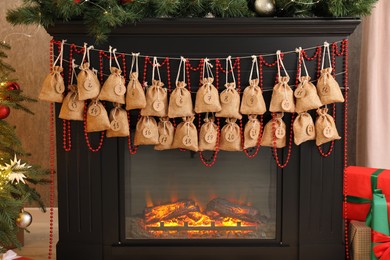 Photo of Advent calendar with gifts and decor hanging on fireplace Christmas near tree indoors