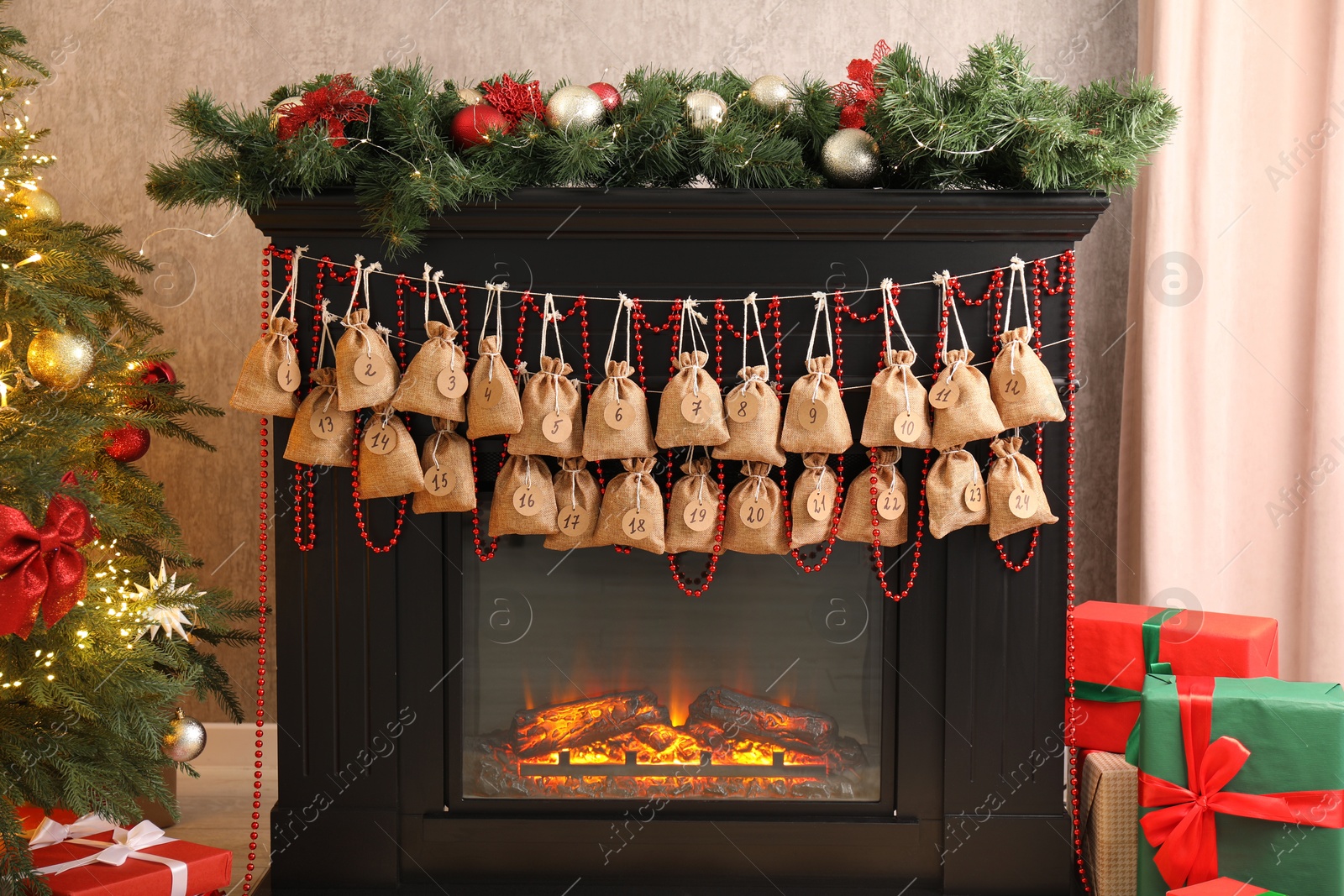 Photo of Advent calendar with gifts and decor hanging on fireplace Christmas near tree indoors