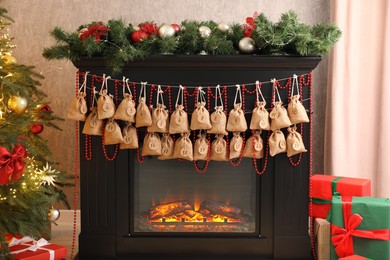 Photo of Advent calendar with gifts and decor hanging on fireplace Christmas near tree indoors