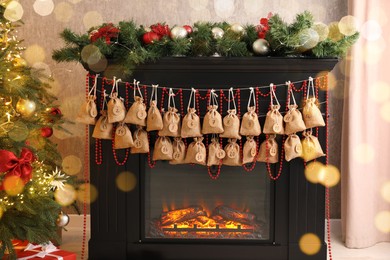 Photo of Advent calendar with gifts and decor hanging on fireplace Christmas near tree indoors