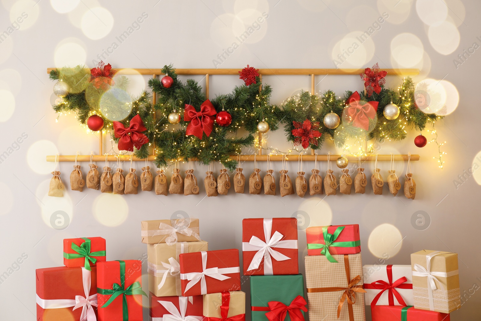 Photo of Christmas advent calendar with gifts and decor hanging on white wall indoors