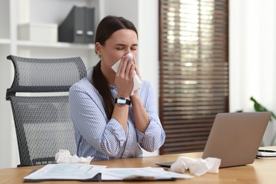 Photo of Sick woman with runny nose at table in office