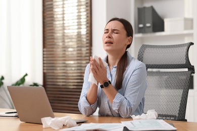 Photo of Sick woman with runny nose at table in office