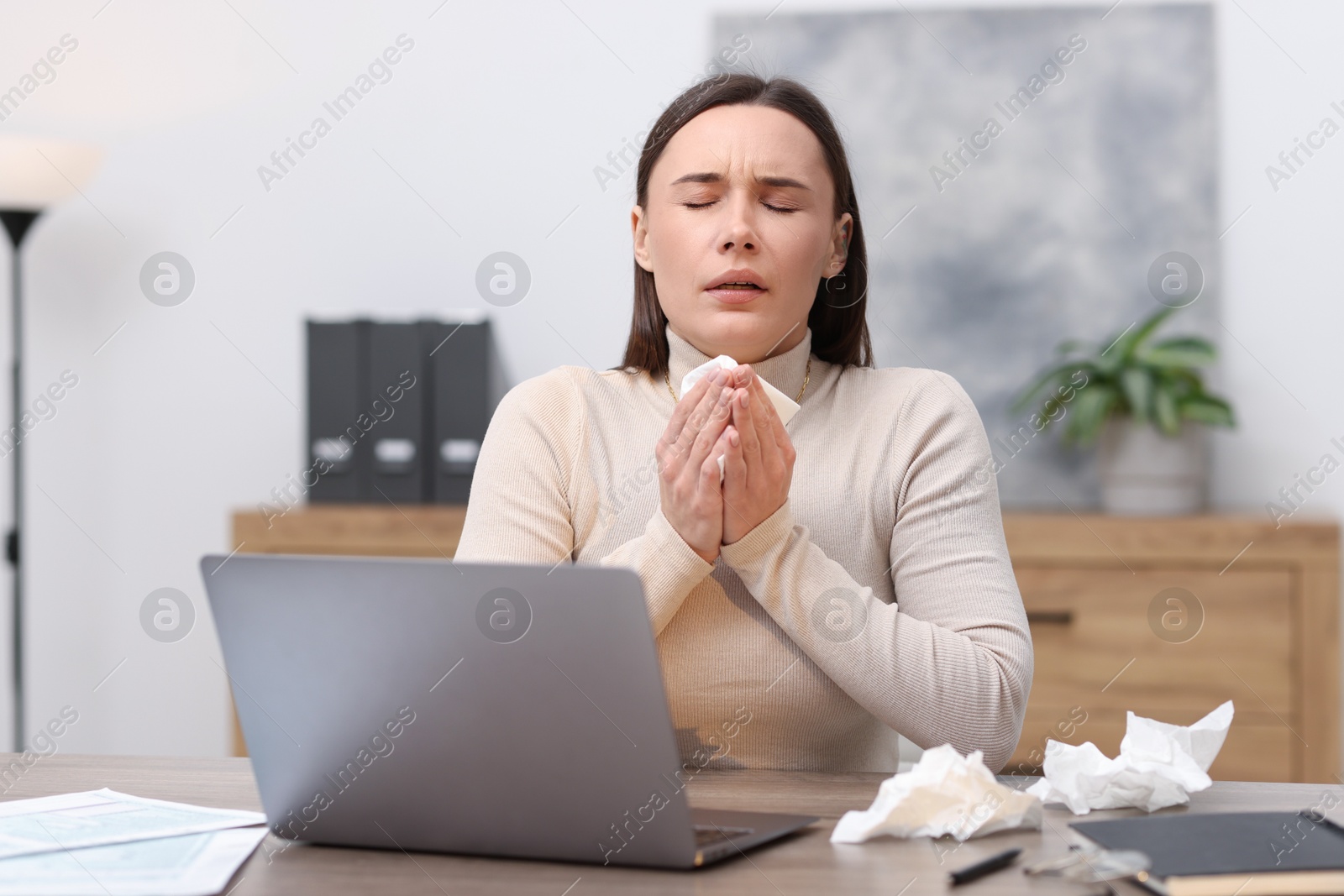 Photo of Sick woman with runny nose at table in office