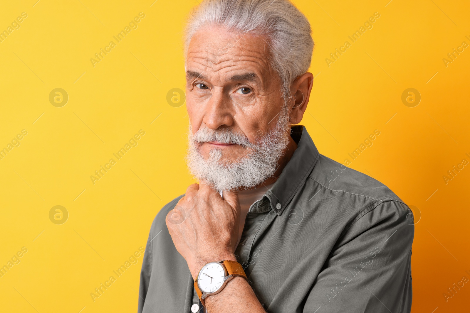 Photo of Portrait of senior man with gray beard on orange background