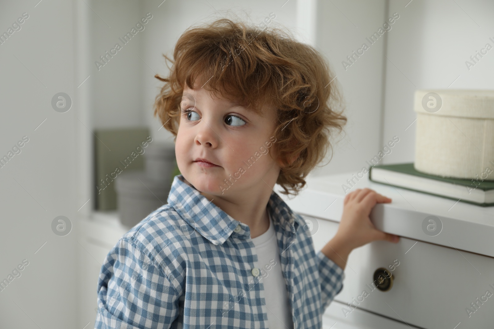 Photo of Little boy near chest of drawers at home