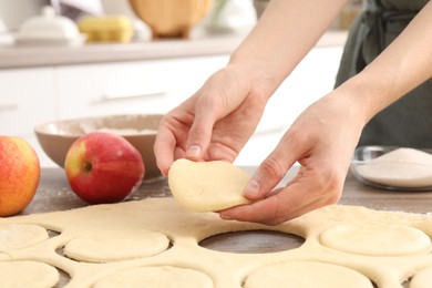 Photo of Woman making pirozhki (stuffed pastry pies) at wooden table indoors, closeup