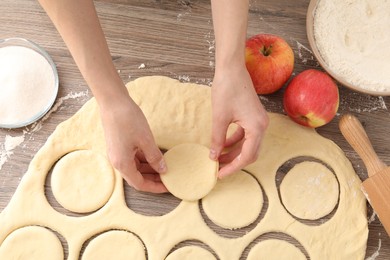 Photo of Woman making pirozhki (stuffed pastry pies) at wooden table, top view