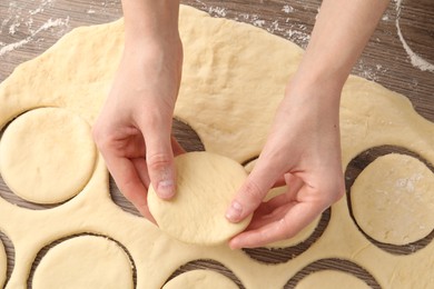 Photo of Woman making pirozhki (stuffed pastry pies) at wooden table, top view