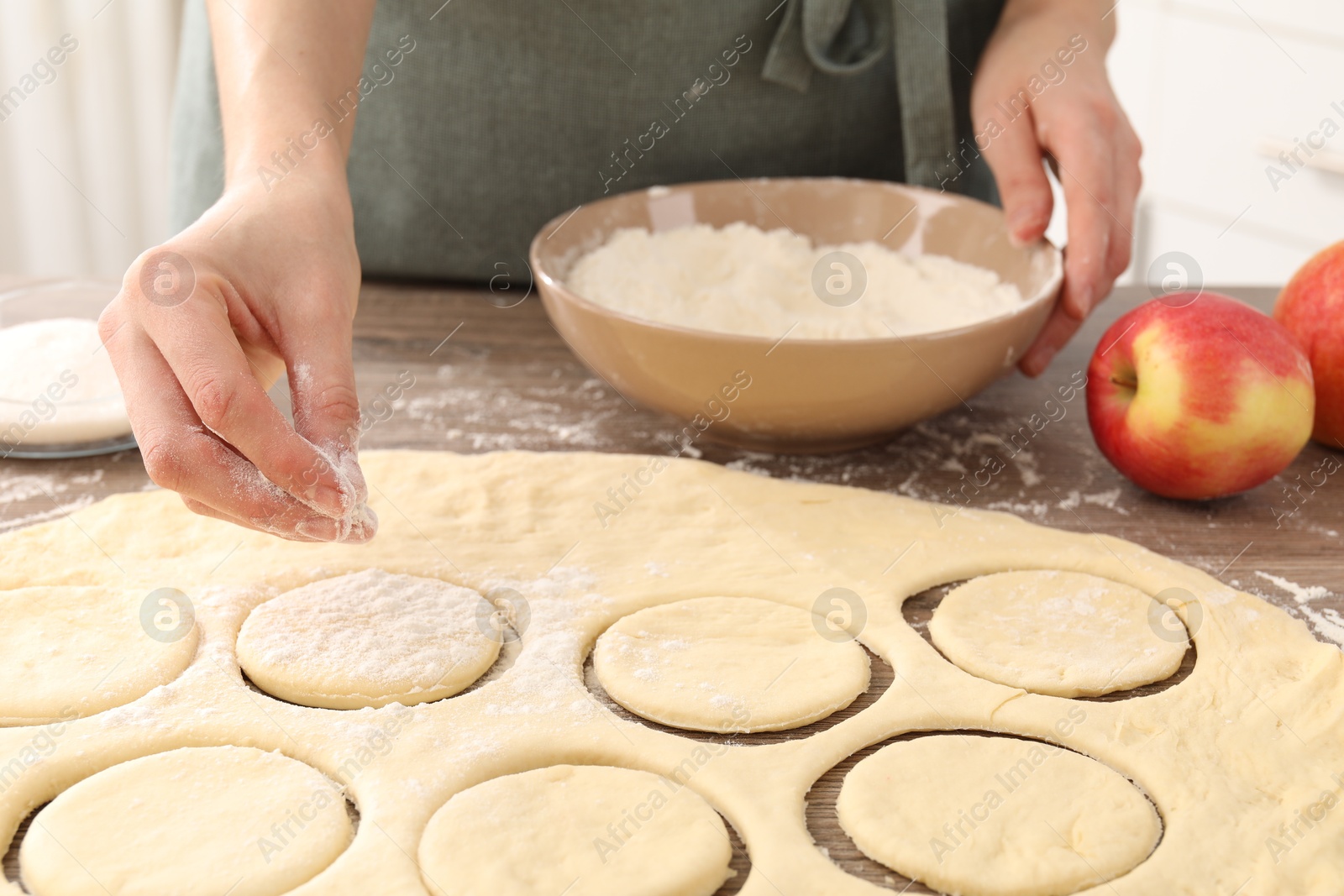 Photo of Woman making pirozhki (stuffed pastry pies) at wooden table indoors, closeup