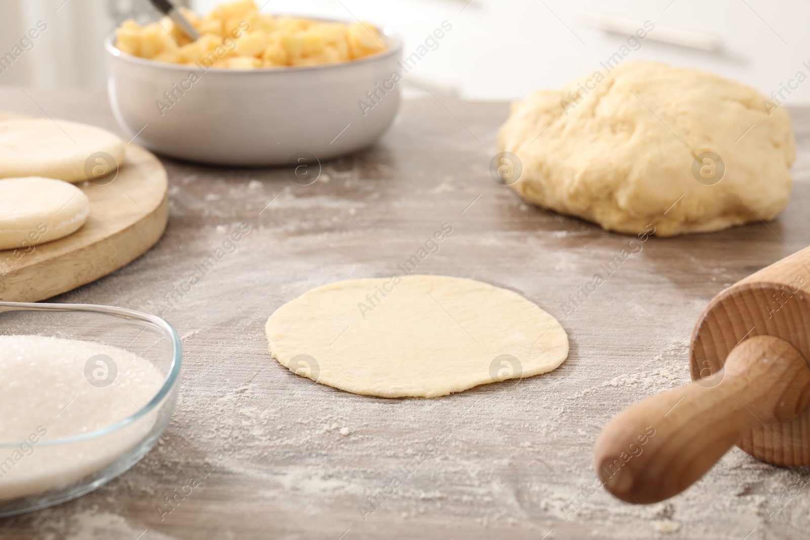 Photo of Making pirozhki (stuffed pastry pies). Pieces of dough on wooden table, closeup