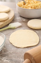 Photo of Making pirozhki (stuffed pastry pies). Pieces of dough on wooden table, closeup