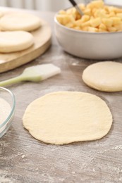 Photo of Making pirozhki (stuffed pastry pies). Pieces of dough on wooden table, closeup