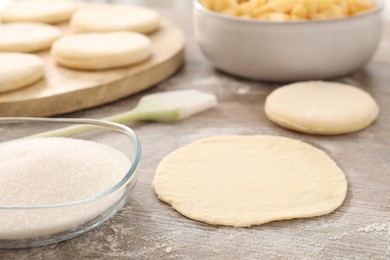 Photo of Making pirozhki (stuffed pastry pies). Pieces of dough on wooden table, closeup