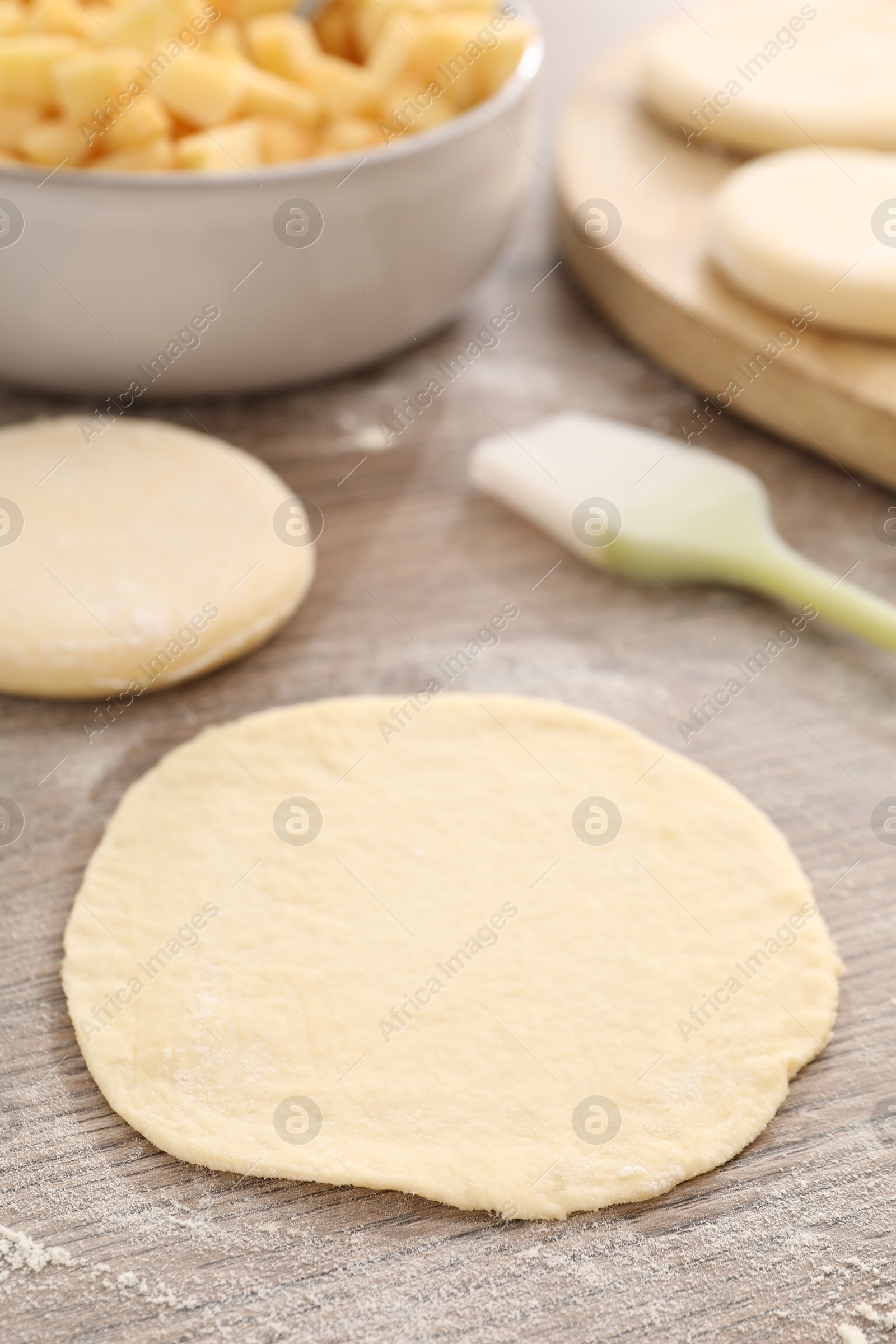 Photo of Making pirozhki (stuffed pastry pies). Pieces of dough on wooden table, closeup