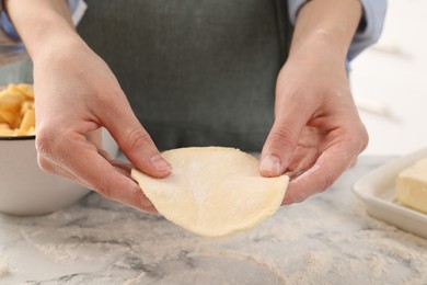 Photo of Woman making pirozhki (stuffed pastry pies) at white marble table indoors, closeup