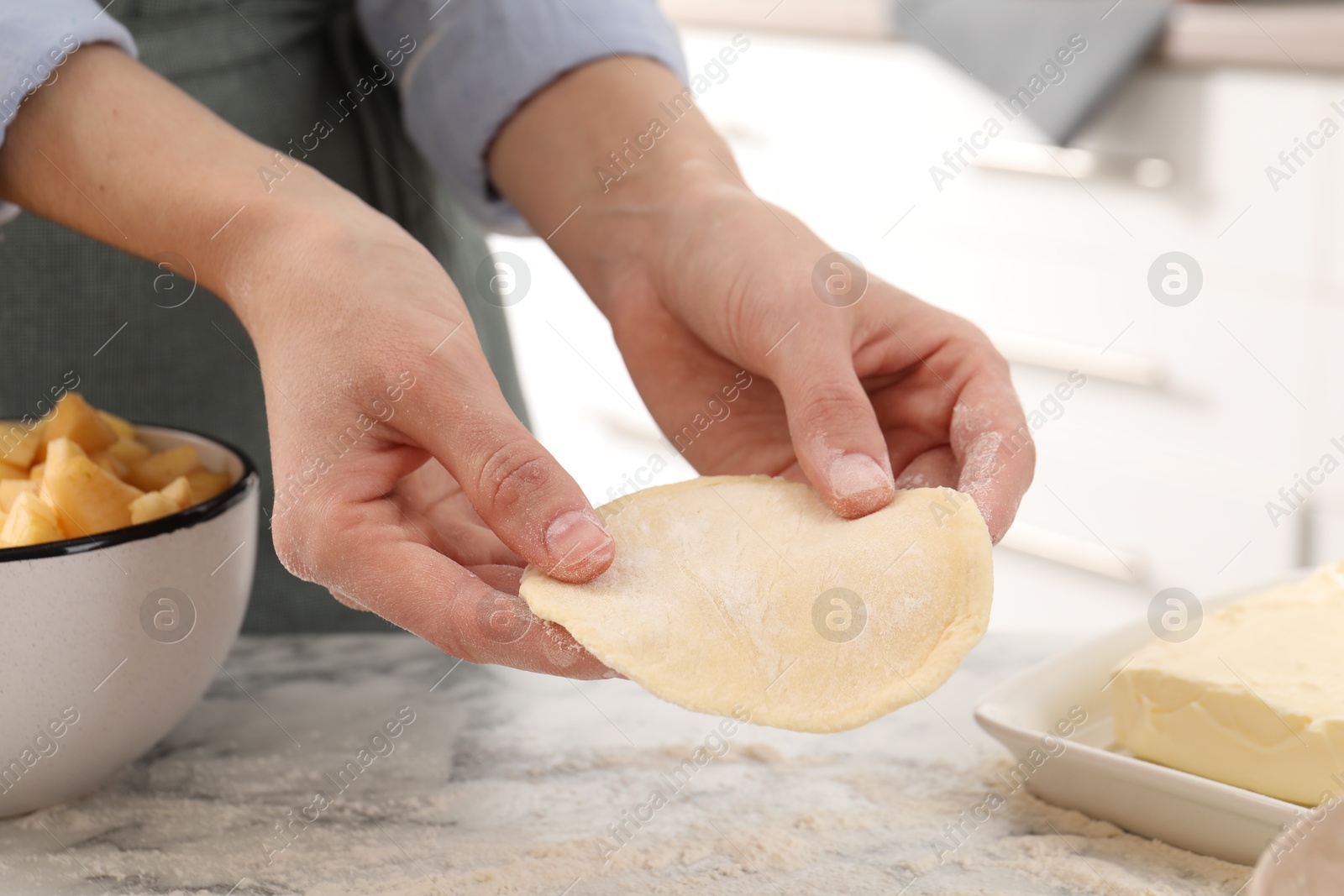 Photo of Woman making pirozhki (stuffed pastry pies) at white marble table indoors, closeup