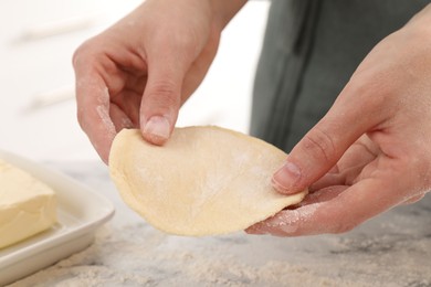 Photo of Woman making pirozhki (stuffed pastry pies) at white marble table indoors, closeup