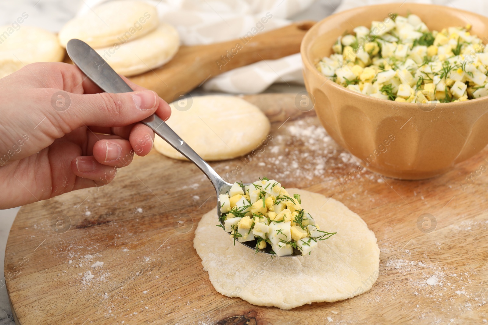 Photo of Woman making pirozhki (stuffed pastry pies) with eggs and dill at table, closeup