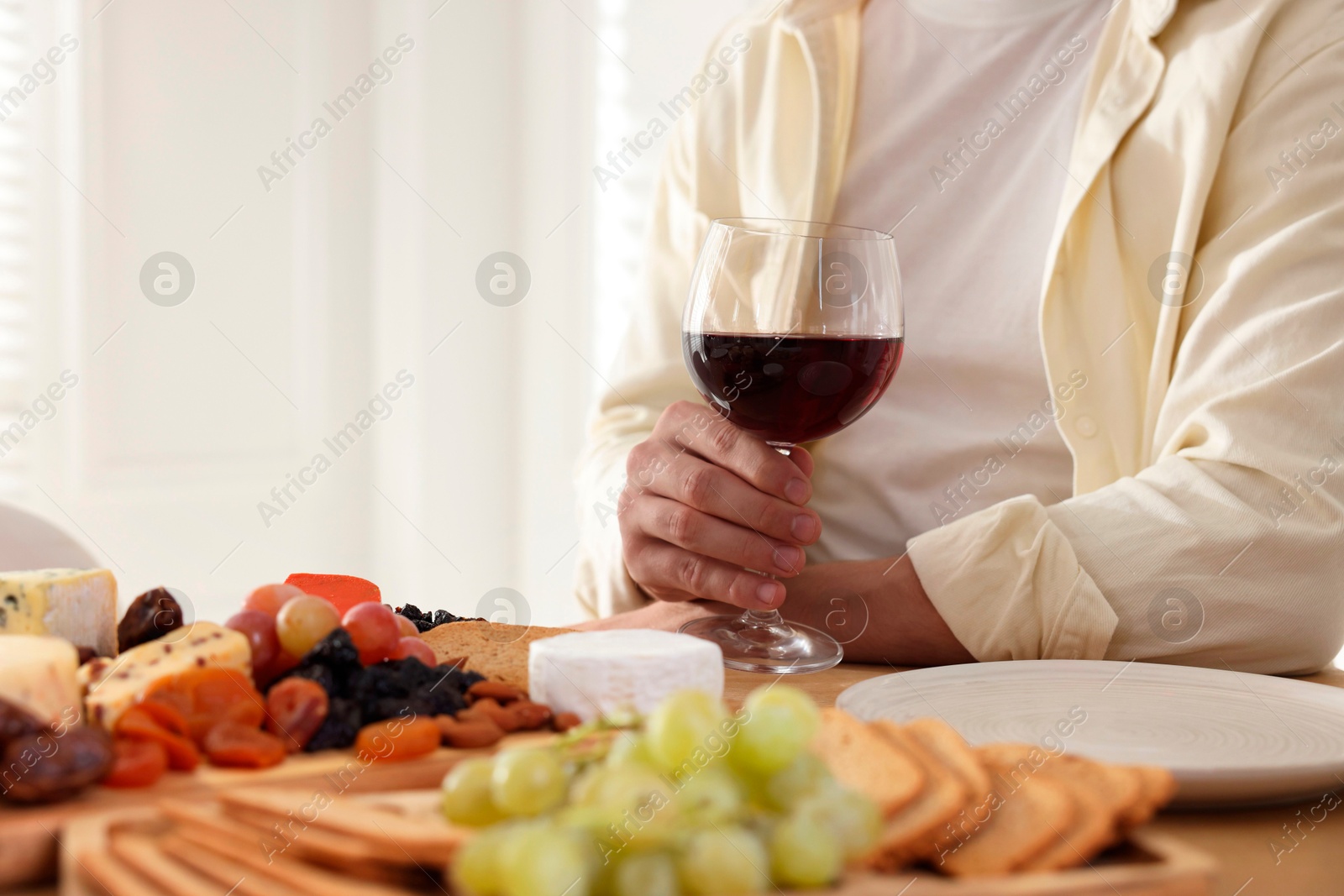 Photo of Man with glass of red wine at table, closeup