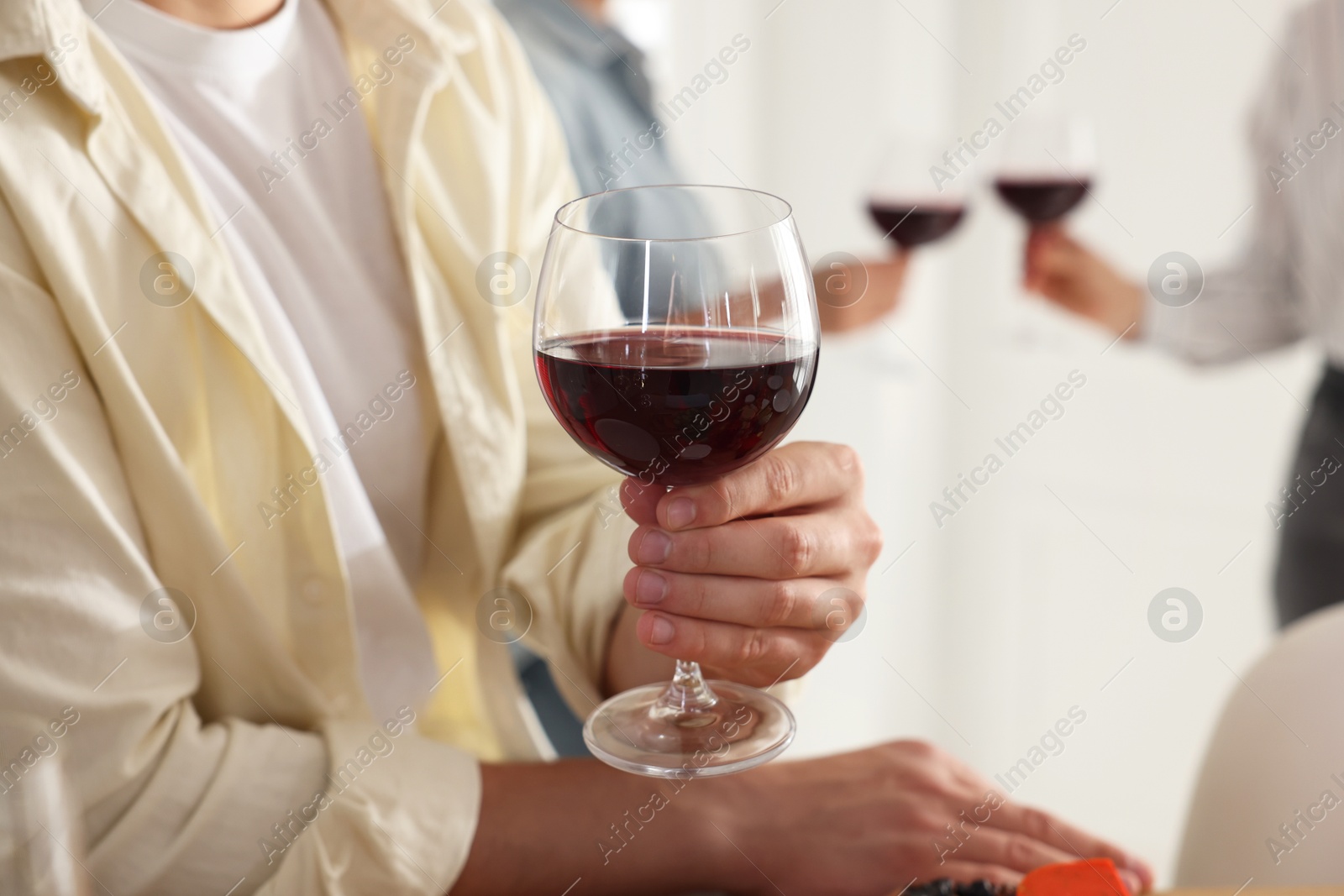 Photo of People with glasses of red wine indoors, selective focus