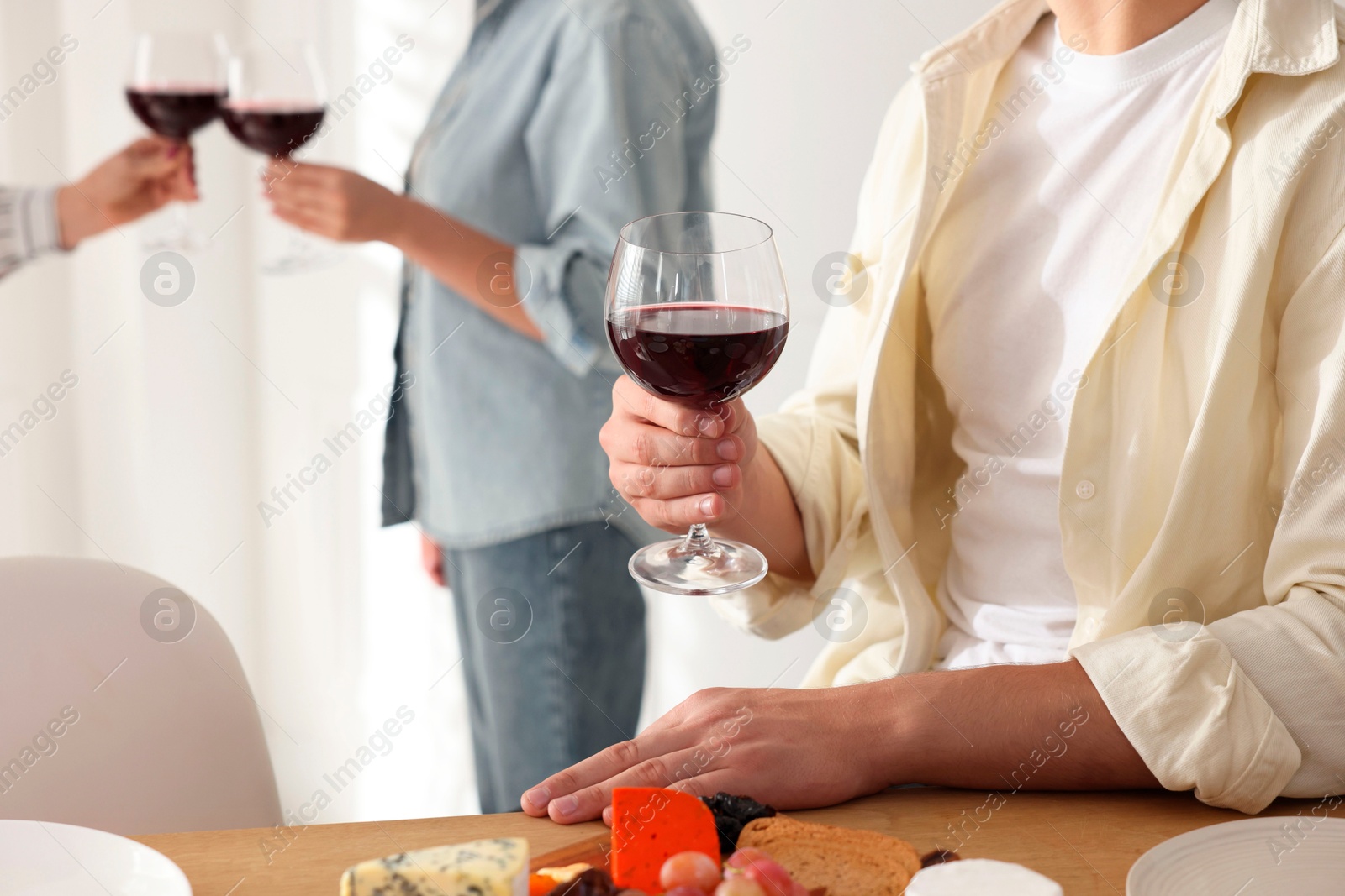 Photo of People with glasses of red wine indoors, selective focus