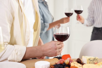 Photo of People with glasses of red wine indoors, selective focus