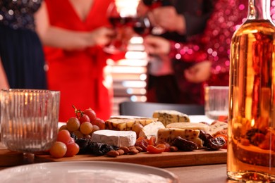 Photo of People clinking glasses of wine at party, focus on table with snacks