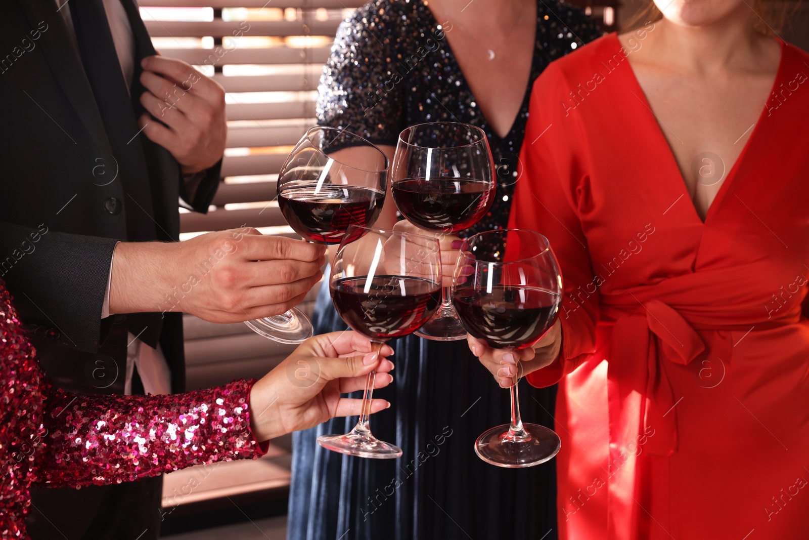 Photo of People clinking glasses of red wine at party, closeup