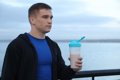 Photo of Athletic man with shaker of protein drink outdoors