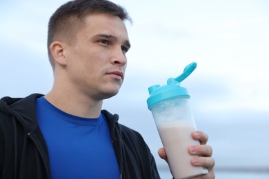 Photo of Athletic man with shaker of protein drink outdoors