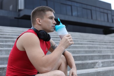 Photo of Handsome athletic man drinking protein shake outdoors